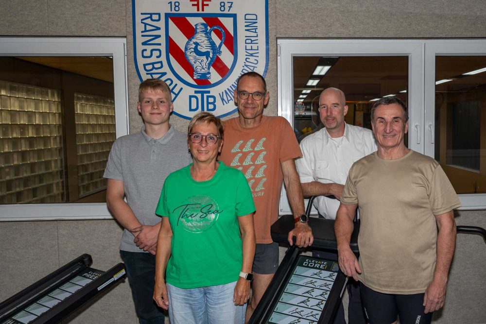 Der Vorstand des TV Ransbach steht im Fitnessgeräteraum der Turnhalle des Turnvereins für ein Gruppenfoto zusammen.